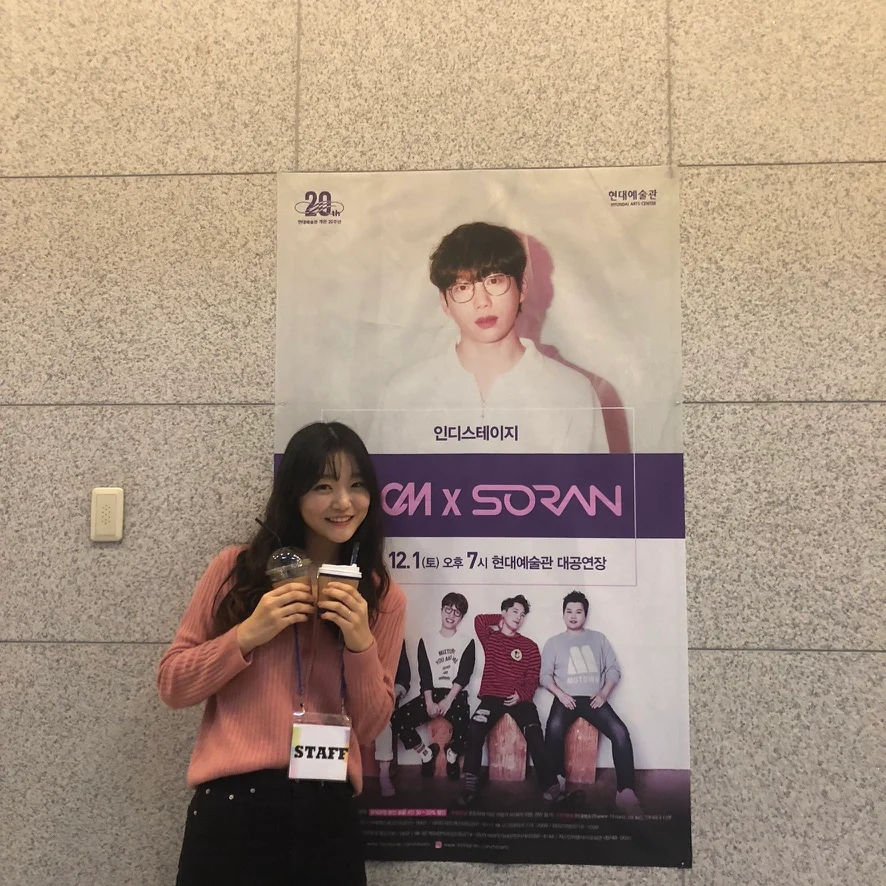 Wearing a staff pass beside a concert poster