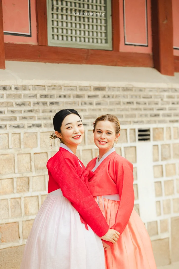 Two models in colorful hanbok beside a traditional building