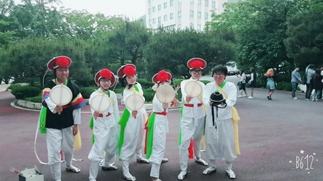 Performers posing with small traditional percussion instruments