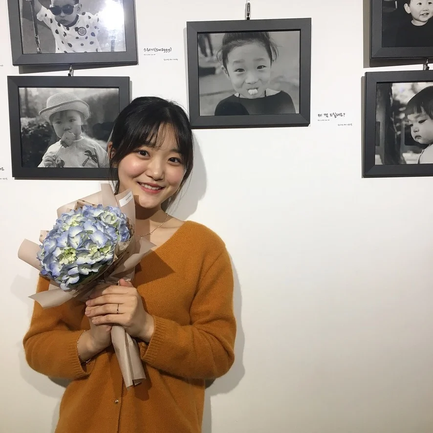 Standing with flowers in front of displayed photographs