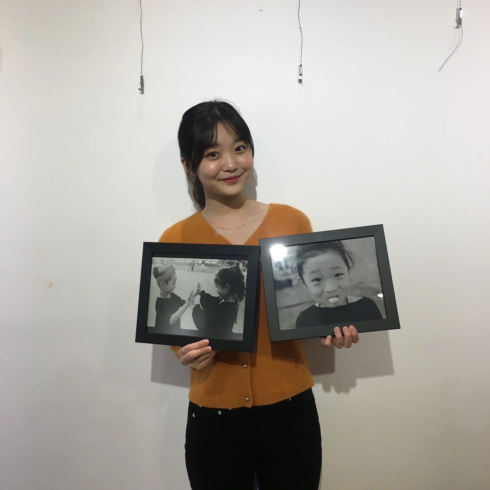 Holding two framed black-and-white photographs