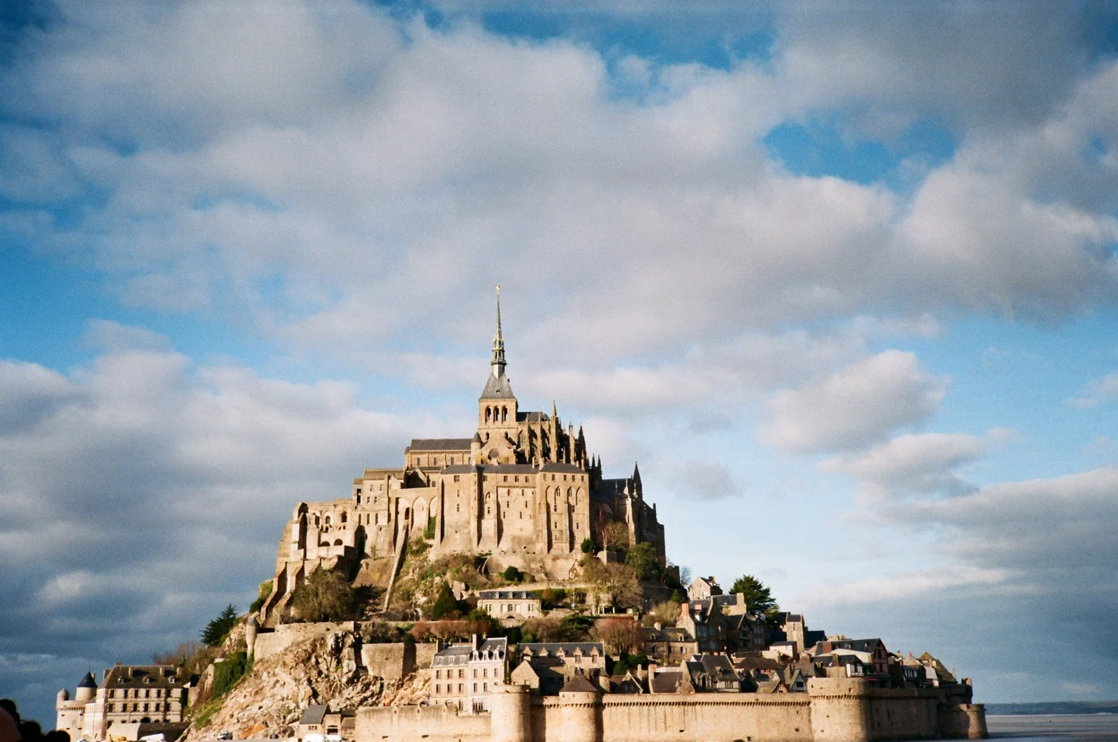 A historic island and abbey beneath a broad sky, photographed on film