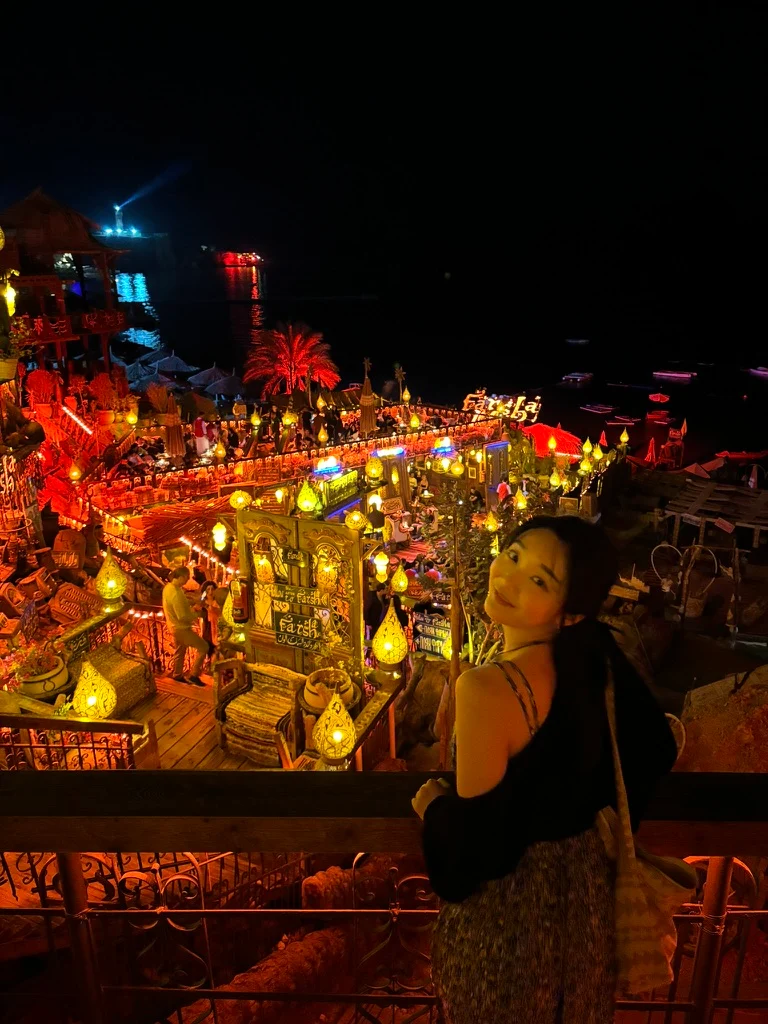 A traveler overlooking a brightly lit seaside venue