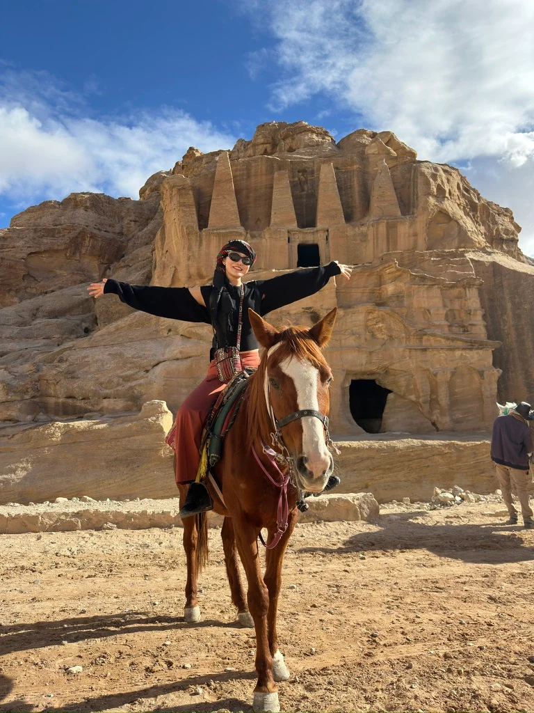 A traveler riding a horse beside a rock-cut monument