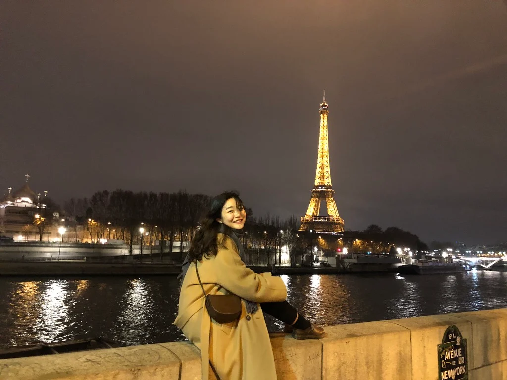 A traveler beside a river with the Eiffel Tower in the background