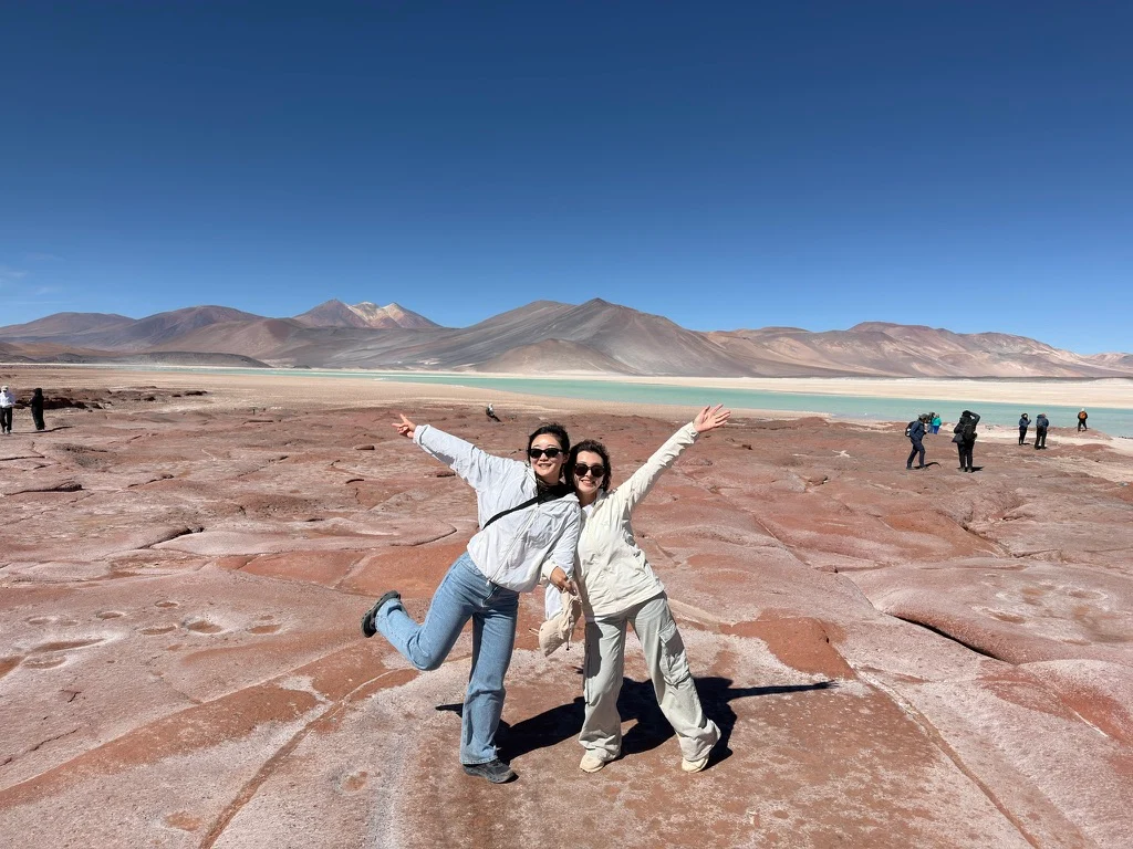 Two travelers beside a colorful high-altitude landscape