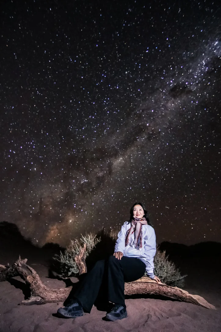 A traveler seated beneath a star-filled night sky