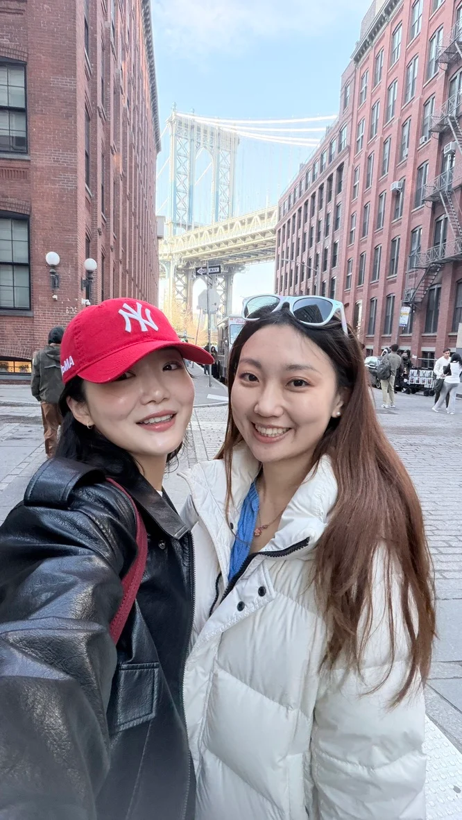 Two people in front of a bridge between city buildings