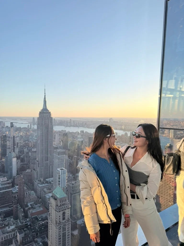 Two people at a city observation deck at sunset