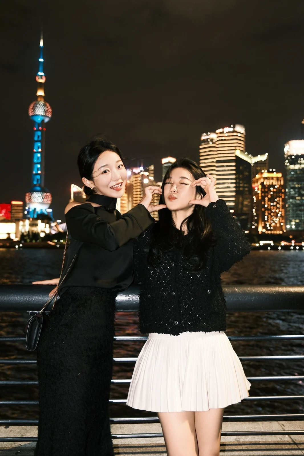 Two people posing beside an illuminated city skyline