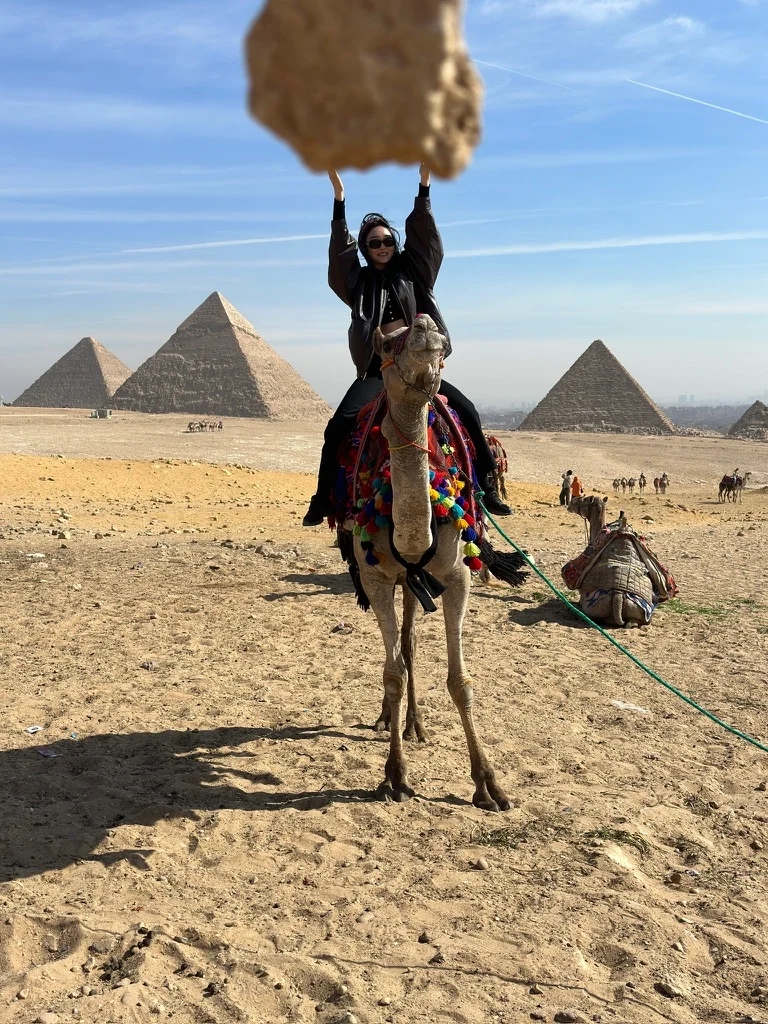 A traveler on a camel in front of pyramids