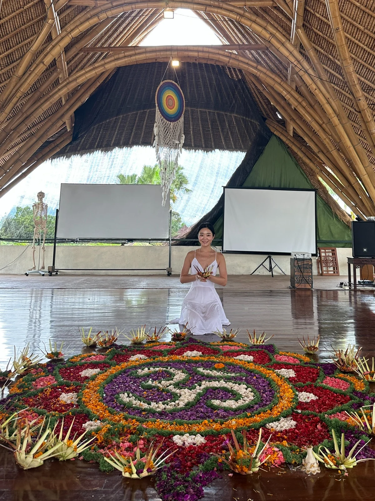 Seated beside a floral arrangement in the yoga studio
